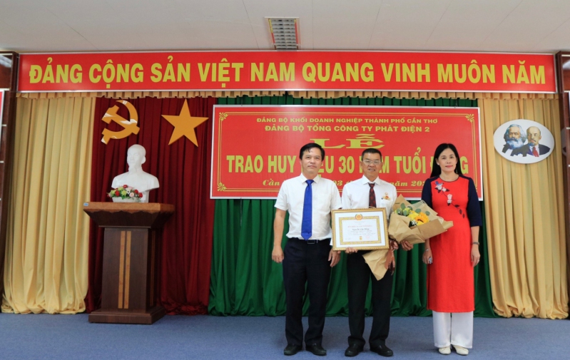 Đ/c Nguyễn Thị Kim Phương - Phó Bí thư ĐUKDNCT (bên phải) và  Đ/c Lê Quốc Vũ – Ủy viên BTV Đảng ủy TCTPĐ 2 (bên trái) trao Huy hiệu và hoa cho đồng chí Nguyễn Văn Đống.